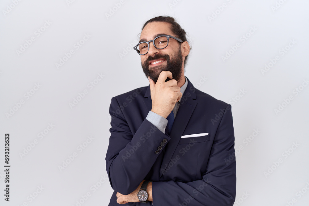 Hispanic man with beard wearing suit and tie looking confident at the camera smiling with crossed arms and hand raised on chin. thinking positive. Hispanic man with beard wearing suit and tie looking confident at the camera smiling with crossed arms and hand raised on chin. thinking positive.