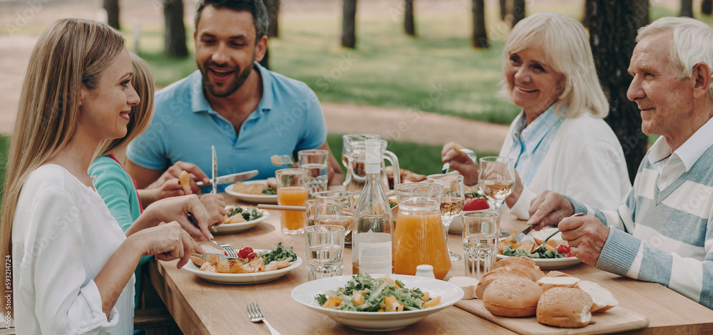Happy multi-generation family enjoying meal while having dinner outdoors together