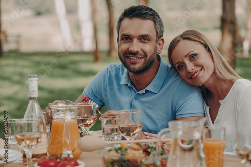 Happy young couple looking at camera while enjoying dinner outdoors together