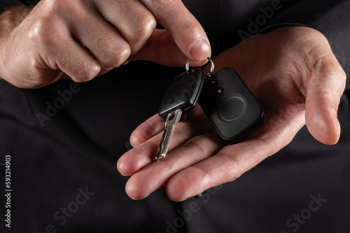 Male hand holding car key, on dark background