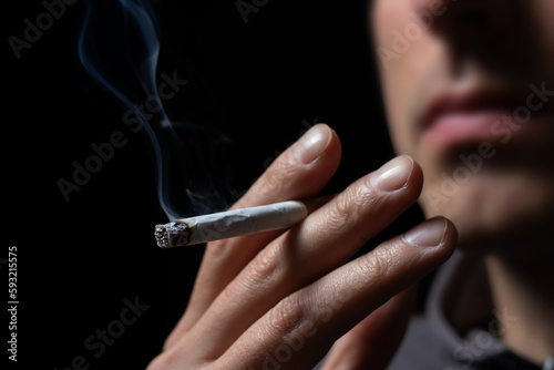 Smoking cigarette in the hand of young man close up