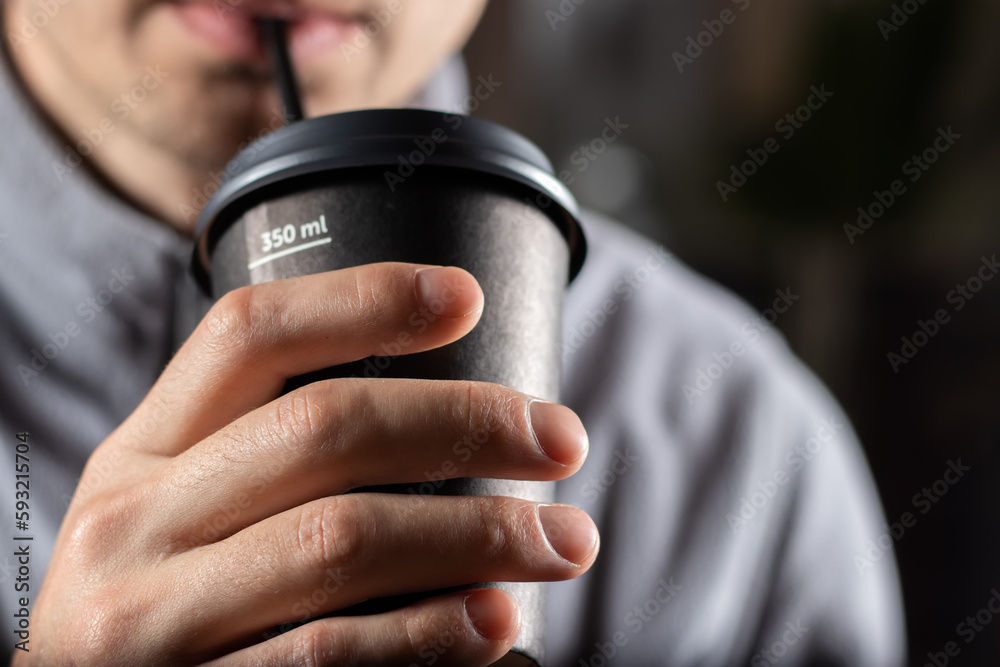 Man drinking coffee from disposable cup with cocktail tube close up