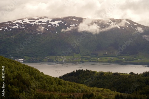 Norwegian fjord with snowy peaks and a cloudy sky in the background, Norway