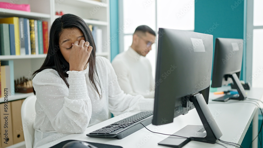 Man and woman students using computer stressed at university classroom Man and woman students using computer stressed at university classroom