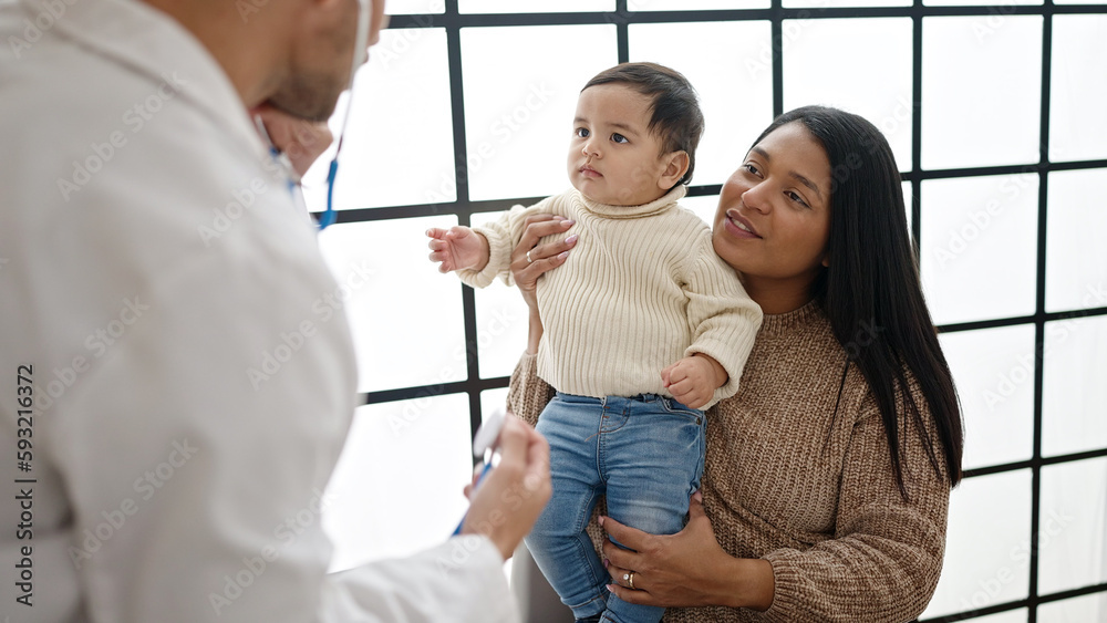 Couple and son examining baby with stethoscope at clinic Couple and son examining baby with stethoscope at clinic