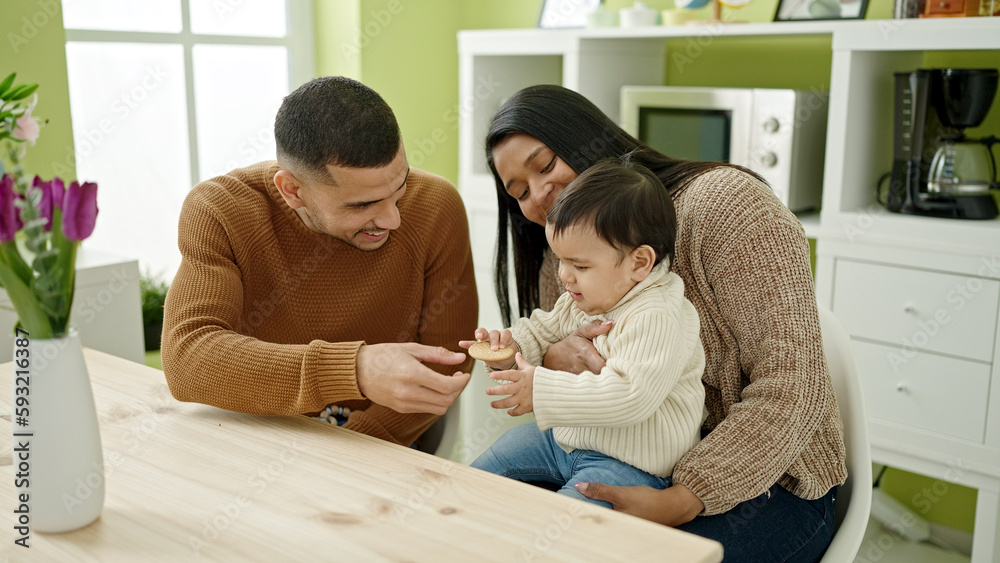 Couple and son sitting on table eating cookie at home Couple and son sitting on table eating cookie at home