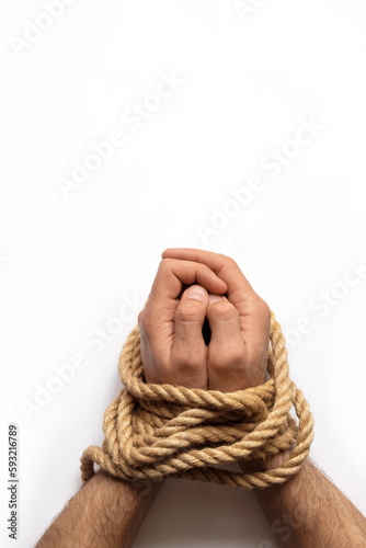 Male hands tied by a rough rope on white background. Top view.