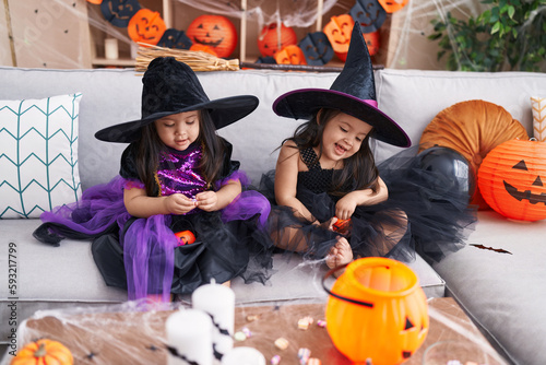 Adorable twin girls having halloween party holding pumpkin baskets at home