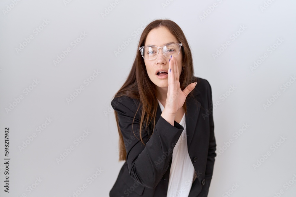 Beautiful brunette woman wearing business jacket and glasses hand on mouth telling secret rumor, whispering malicious talk conversation Beautiful brunette woman wearing business jacket and glasses hand on mouth telling secret rumor, whispering malicious talk conversation