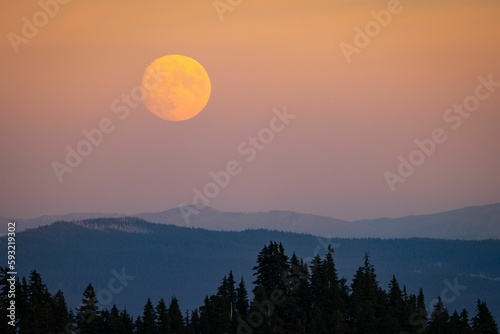 Beautiful landscape of a full neon moon over the mountains in a purple sky