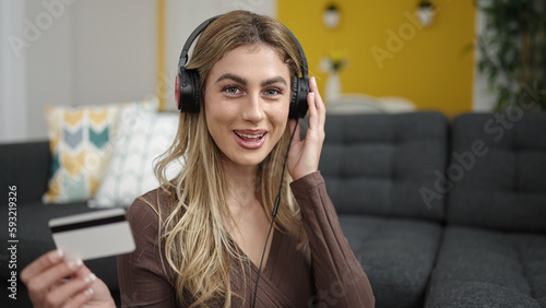 Young blonde woman having video call holding credit card at home