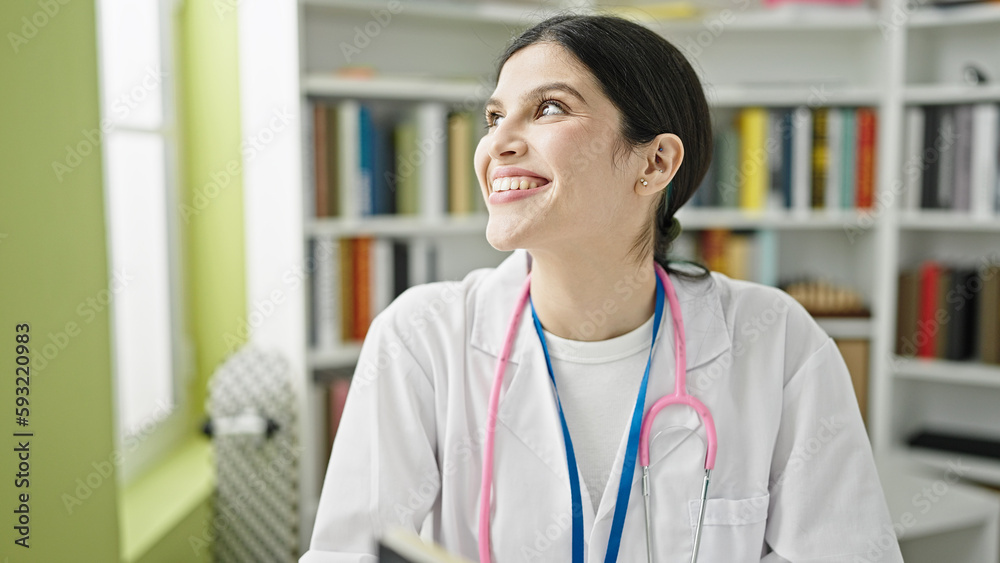 Young beautiful hispanic woman doctor sitting on table smiling confident at library university Young beautiful hispanic woman doctor sitting on table smiling confident at library university