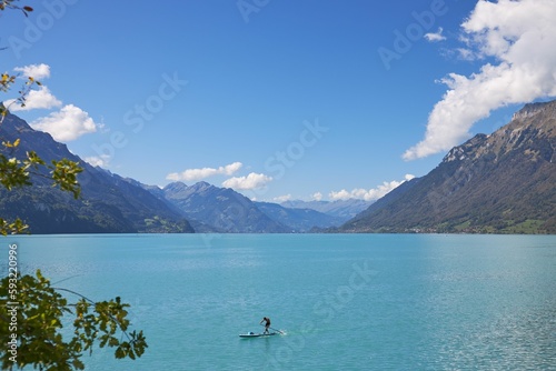 Scenic view of a person paddleboarding in the tranquil lake Breinz surrounded by mountains in summer