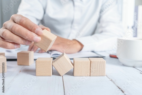 Businessman holding small wooden blocks while sitting at his desk