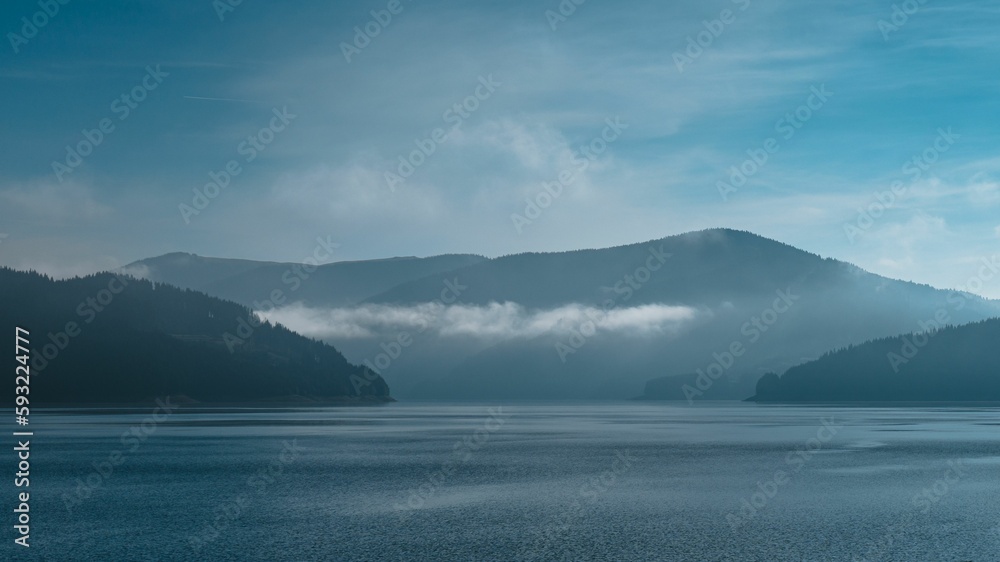 Scenic lake surrounded by mountains and a blue sky