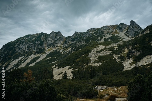 Aerial view of rocky mountains with green vegetation under blue cloudy sky