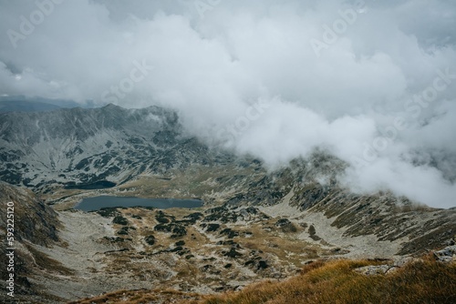 Beautiful view of a rocky mountain landscape with small lake in fog