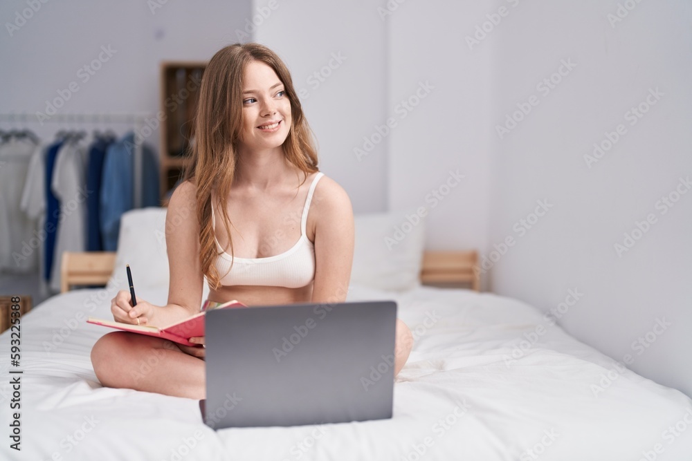 Young woman using laptop writing on notebook at bedroom Young woman using laptop writing on notebook at bedroom