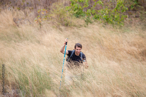 Caucasian man alone walking in gold grass hiking with backpack, Looking for goals ahead. hiking touring, Facing future challenges concept.