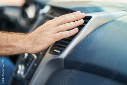 Young caucasian man touching air condition car at street