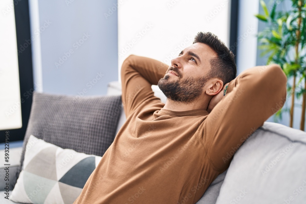 Young hispanic man relaxed with hands on head sitting on sofa at home Young hispanic man relaxed with hands on head sitting on sofa at home