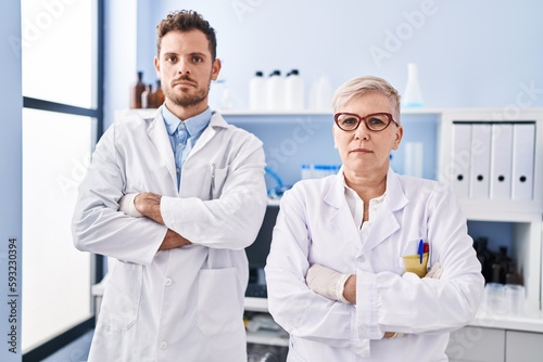 Mother and son scientist partners standing with arms crossed gesture at laboratory