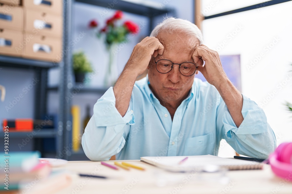 © Krakenimages.com - Senior grey-haired man artist drawing on notebook with doubt expression at art studio