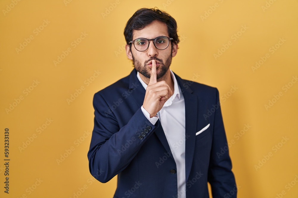 Handsome latin man standing over yellow background asking to be quiet with finger on lips. silence and secret concept. Handsome latin man standing over yellow background asking to be quiet with finger on lips. silence and secret concept.
