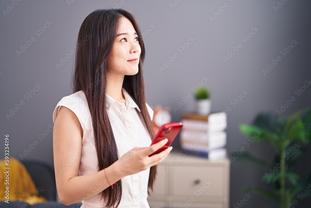 Young chinese woman using smartphone standing at home Young chinese woman using smartphone standing at home