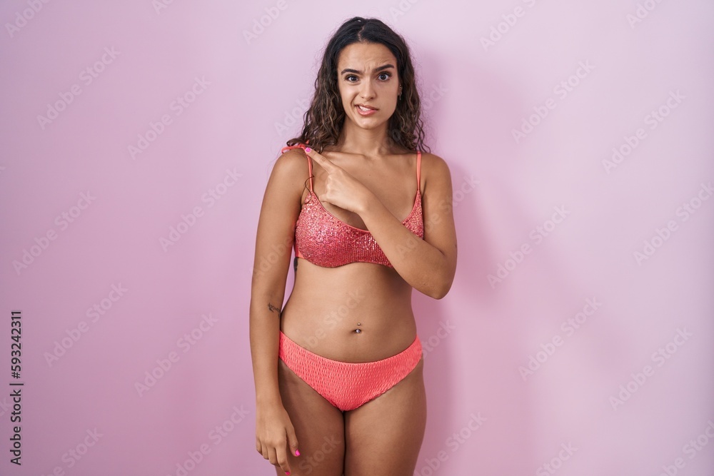 Young hispanic woman wearing lingerie over pink background pointing aside worried and nervous with forefinger, concerned and surprised expression Young hispanic woman wearing lingerie over pink background pointing aside worried and nervous with forefinger, concerned and surprised expression