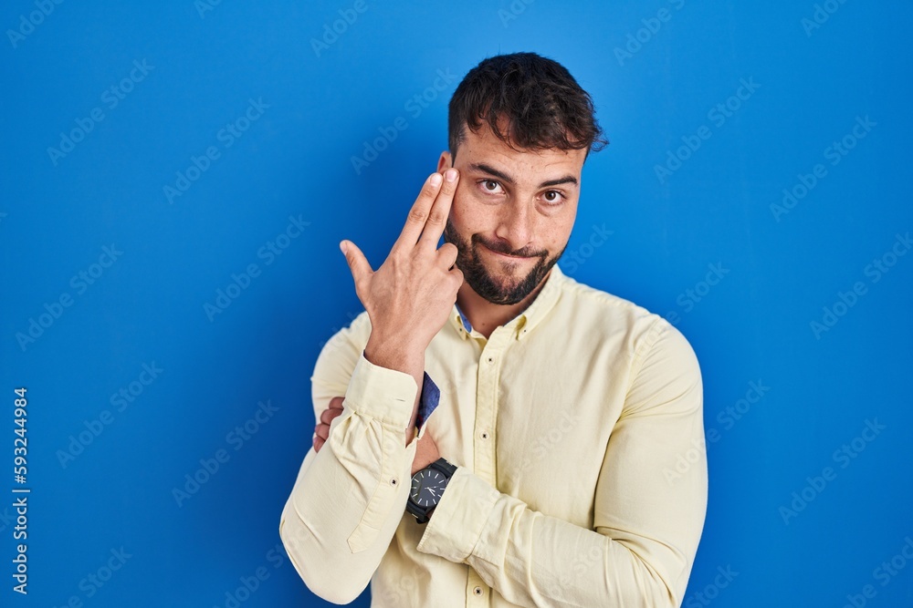 Handsome hispanic man standing over blue background shooting and killing oneself pointing hand and fingers to head like gun, suicide gesture. Handsome hispanic man standing over blue background shooting and killing oneself pointing hand and fingers to head like gun, suicide gesture.