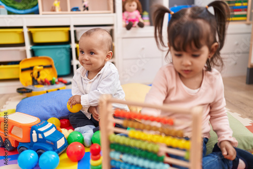 Adorable boy and girl playing with abacus sitting on floor at kindergarten