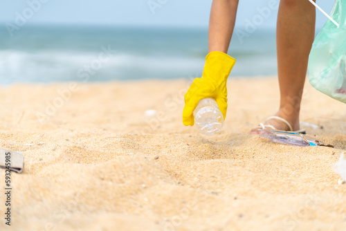 Asian family travel ocean on summer holiday vacation. Adult woman hand picking up plastic trash and garbage on the beach in sunny day. Environmental conservation earth day and waste pollution concept.