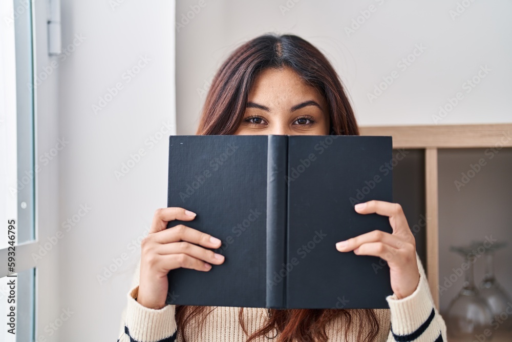 Young hispanic woman smiling confident covering face with book at home Young hispanic woman smiling confident covering face with book at home