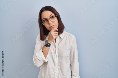 Young hispanic woman standing over white background thinking worried about a question, concerned and nervous with hand on chin