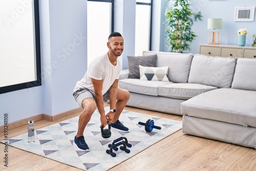 African american man smiling confident using kettlebell training at home