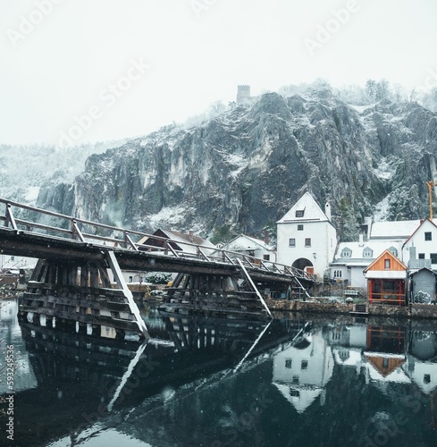 Vertical shot of the river reflecting the houses and the snow-covered mountains, Kelheim, Germany