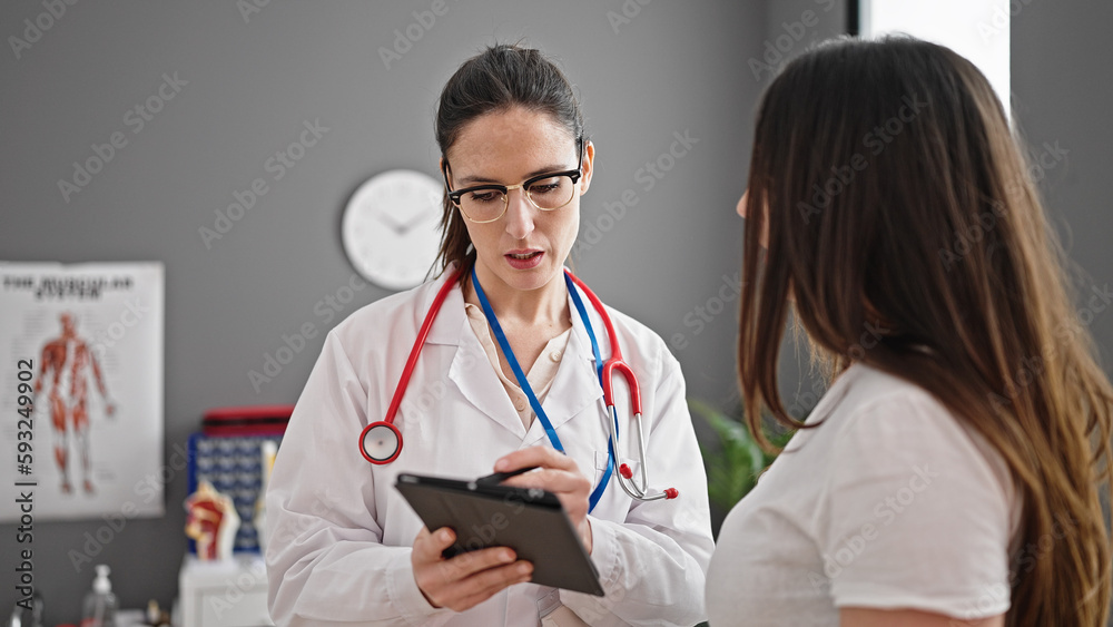 Fototapeta premium Two women doctor and patient using touchpad having consultation at clinic