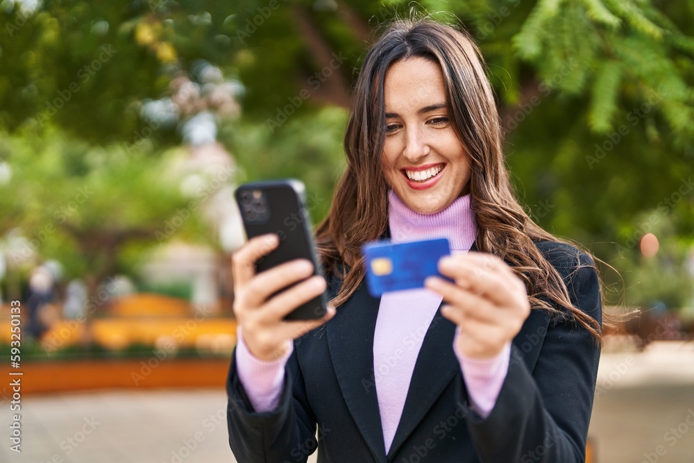 Young hispanic woman using smartphone and credit card at park Young hispanic woman using smartphone and credit card at park