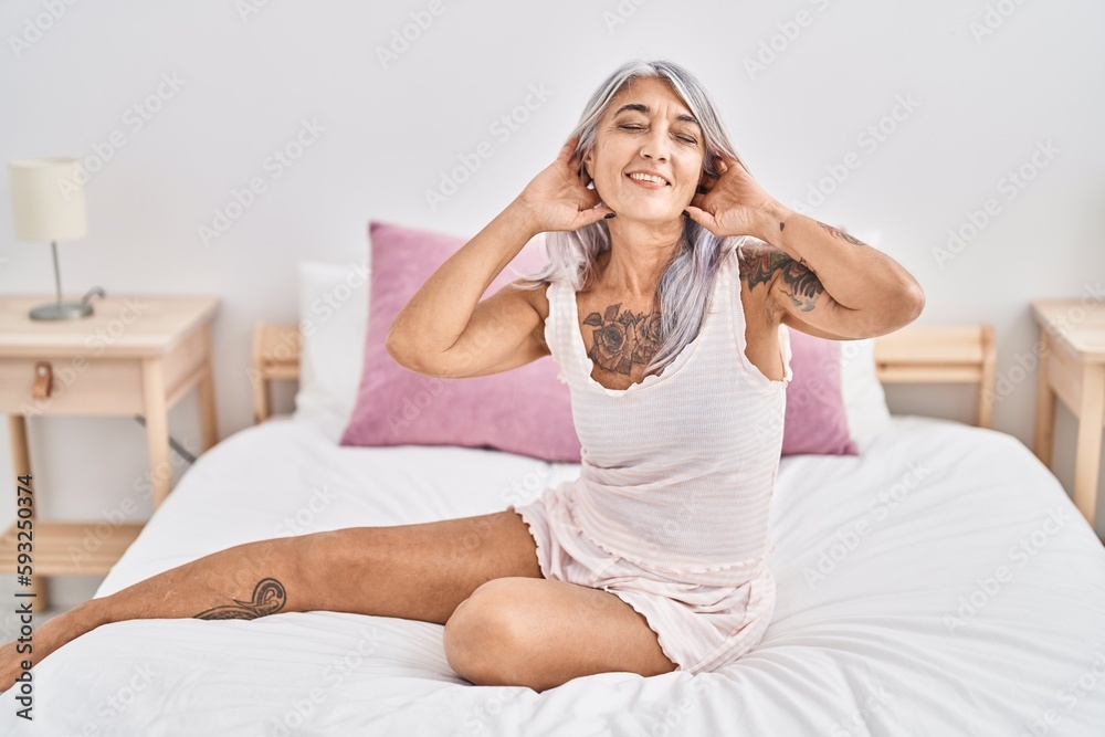 Middle age grey-haired woman smiling confident sitting on bed at bedroom Middle age grey-haired woman smiling confident sitting on bed at bedroom
