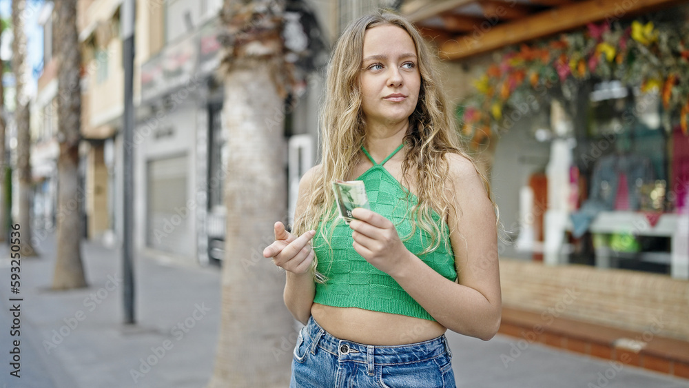 Young blonde woman counting israel shekels banknotes at street