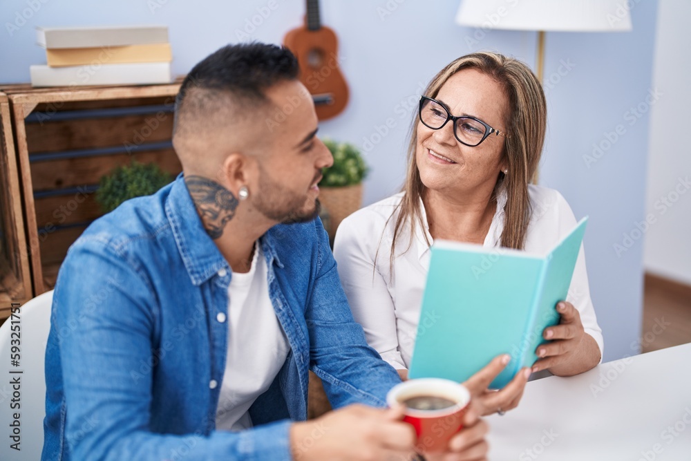 Man and woman mother and son drinking coffee reading book at home Man and woman mother and son drinking coffee reading book at home