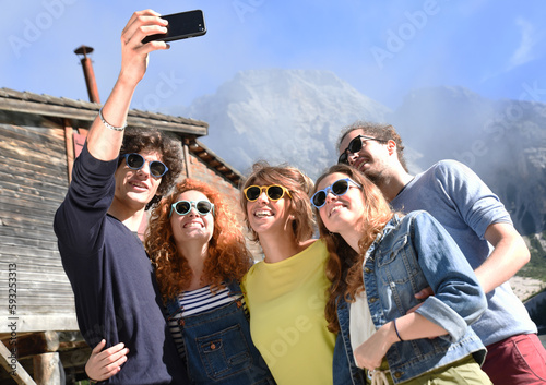Group of friends of different nationalities on vacation on a mountain lake in the middle of nature, take selfie and celebrate spring or summer