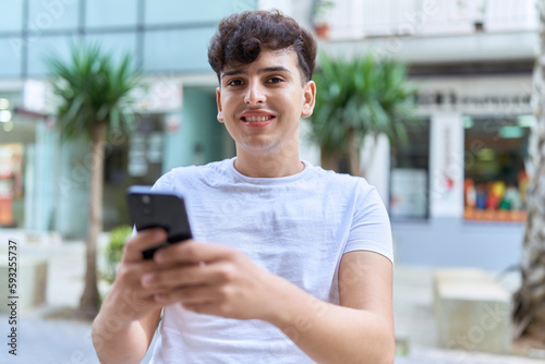 Non binary man smiling confident using smartphone at street