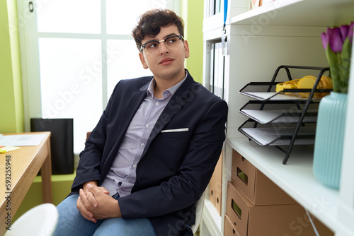 Non binary man business worker smiling confident sitting on table at office
