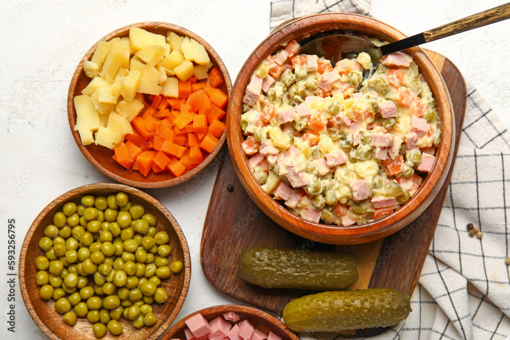 Bowl of tasty Olivier salad and ingredients on light background Bowl of tasty Olivier salad and ingredients on light background