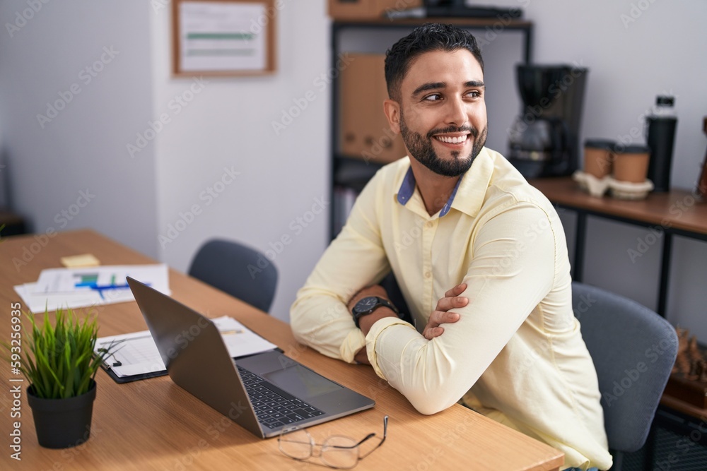 Young arab man business worker using laptop sitting on arms crossed gesture at office Young arab man business worker using laptop sitting on arms crossed gesture at office