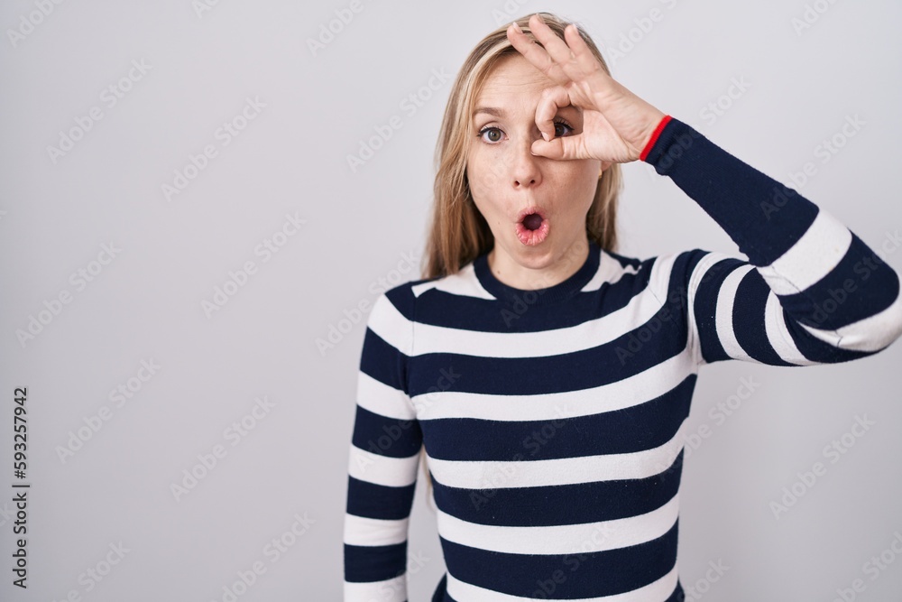 Young caucasian woman wearing casual navy sweater doing ok gesture shocked with surprised face, eye looking through fingers. unbelieving expression. Young caucasian woman wearing casual navy sweater doing ok gesture shocked with surprised face, eye looking through fingers. unbelieving expression.