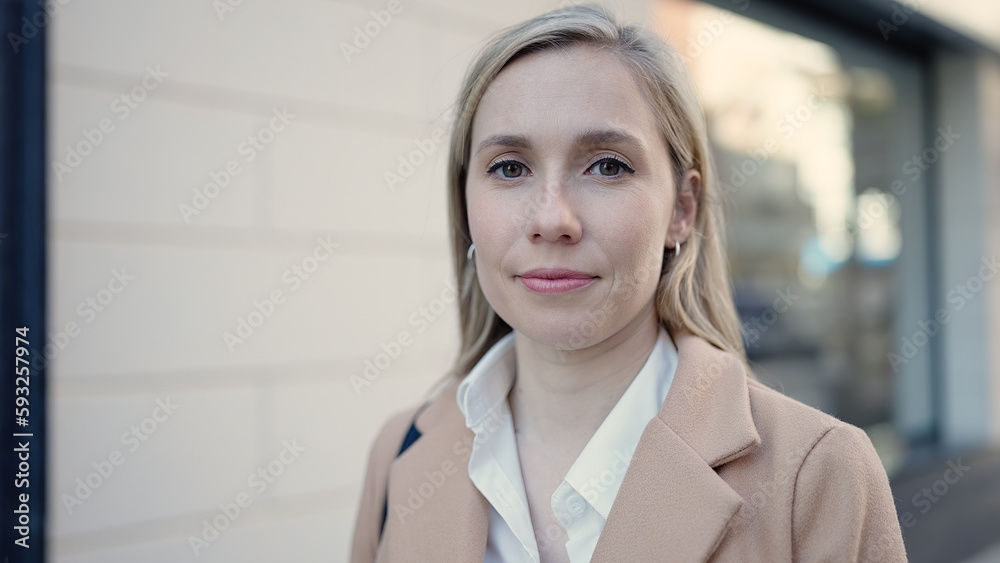 Young blonde woman standing with serious expression at street Young blonde woman standing with serious expression at street