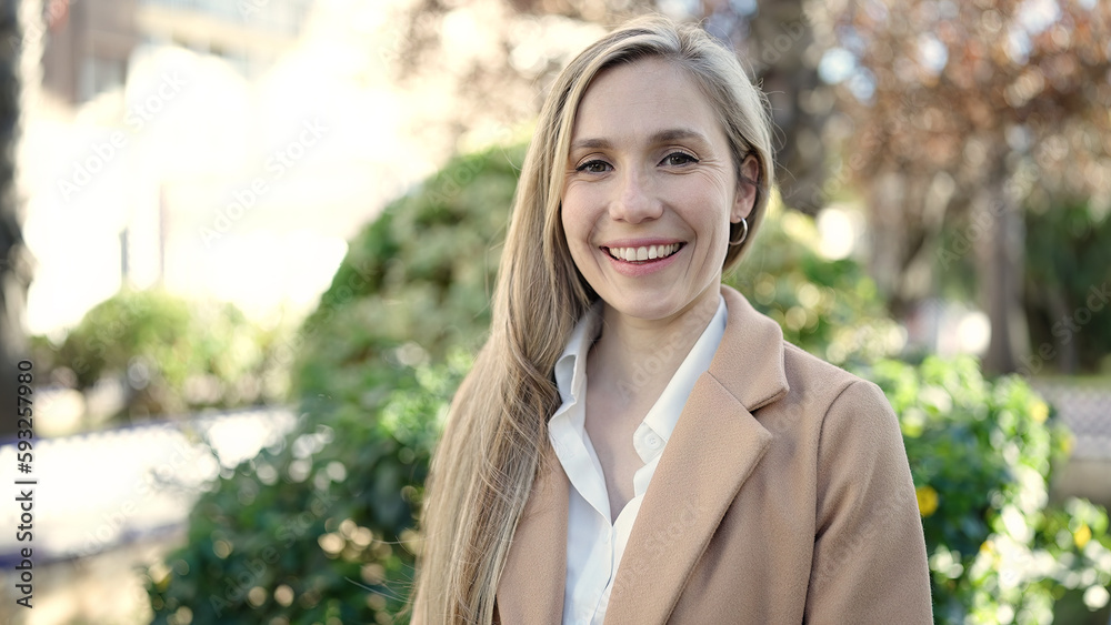 Young blonde woman smiling confident standing at park